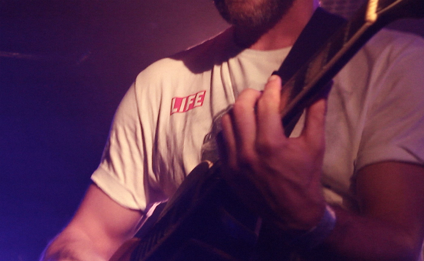 Photographie couleur sur scène en très gros plan sur la main l'artiste Don Frappa qui joue de la guitare - Frappa Studio ©2015